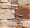 Beige and brown exterior wall cladding made of irregular stone bricks.