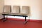 beige chair alignment on red floor in a waiting room