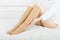 Beige compression stockings on a woman in a white room. Knee socks or socks. Girl putting on stockings at home