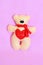 Beige felt Teddy bear, handmade toy. Funny beige bear toy isolated on a pink fabric background
