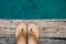 Beige flip-flop sandals on edge of wooden dock over water