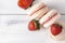 Beige French macaroons   with strawberry  pink cream on a white wooden background, cookies