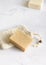 Beige handmade soap bar on soap saver bag on a marble table close up, mockup
