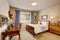 Beige kids room with wooden furniture set, blue curtains and stripped bedding.