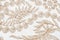 Beige lacy canvas with plant motifs on white background.