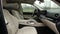 Beige leather interior of a premium SUV with wood trim and a huge multimedia monitor combined with an electronic