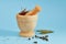 Beige marble mortar with pestle for grinding ingredients near peppercorns and bay leaf lying on a blue background with copy space