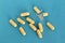 Beige medication capsules lie in a heap on a blue background.