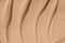 Beige nude liquid foundation smear, concealer texture smudge. Make up base drops, cream textured background. Closeup