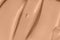 Beige nude liquid foundation smear, concealer texture smudge. Make up base drops, cream textured background. Closeup