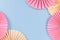 Beige and pink paper craft rosettes in corners of blue background with empty copy space