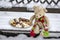 Beige plushy teddy bear with red green striped knitted scarf sitting with Christmas cookies on the bench covered with white snow