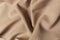 Beige or sand crumpled or wavy fabric texture background. Abstract linen cloth soft waves. Silk atlas or stretch