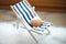 Beige shells of various sizes lie on a little vintage decoration striped beach chair, side view