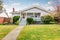 Beige siding house exterior with covered porch and trimmed bushes in front.