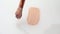 Beige smear of make-up foundation cream with a brush on white background