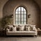 Beige sofa with cushions and plaid against of arched window and stone stucco wall