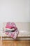 Beige sofa with plaid and colorful pillows pink, grey, white and tray with cups of coffee in the living room