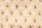 Beige soft tapestry pattern background with symmetrical buttons on the corners of diamonds. Soft and expensive furniture