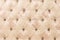 Beige soft tapestry pattern background with symmetrical buttons on the corners of diamonds. Soft and expensive furniture