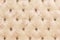 Beige soft tapestry pattern background with symmetrical buttons on the corners of diamonds. Soft and expensive furniture
