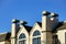 Beige stucco building with four visible chimney vents and metal tops with windows and clear blue copy space background