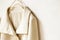 Beige or white jacket hanging on clothes hanger on white background