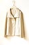 Beige or white jacket hanging on clothes hanger on white background