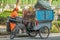 BEIJING / CHINA-JULY 29 2017: A female cleaner is standing by her bicycle with a garbage container on it. She is busy emptying