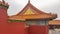 Beijing - A close up on a red wall inside of Forbidden City in Beijing, China. The building has very richly decorated rooftop