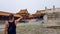 Beijing-A man standing on the square inside of Forbidden City in Beijing, China. He is pointing to a massive gate in front of him