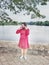 Bekasi, Indonesia, May 1, 2021: Asian woman wearing a red dress  and face mask stands on a lake east of Bekasi