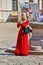 Belarus, Nesvizh August 2019. A girl in an old red dress plays the flute. Folk concert on the square of the old castle