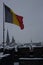 Belgian flag flying in wind on old castle roof with beautiful view at winter town. Historical buildings and castle roofs in snow.