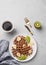 Belgian vegetarian waffles with kiwi, blueberries and banana slices on a white plate with a cup of coffee on a light background