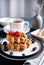Belgian waffles with blueberries and red currants, honey and tea on a white table