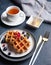 Belgian waffles with blueberries and red currants, honey and tea on a white table