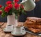 Belgian waffles for breakfast for two. Homemade pastries and a bouquet of red roses on the table. Delicious romantic lunch. Photo