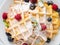 Belgian waffles with raspberries, blueberries, curd, close-up, top view. Healthy homemade breakfast, light concrete background