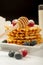 Belgian waffles with raspberries and sieving sugar powder and honey served with jug of milk on a white table