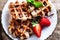 Belgian waffles with strawberries, mint, sugar powder and chocolate syrup on wooden background, image in rustic style with copy