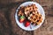 Belgian waffles topped with strawberries, syrup and icing. Homemade breakfast in rustic style, toned image with copy space .