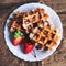 Belgian waffles topped with strawberries, syrup and icing. Homemade breakfast in rustic style, toned image with copy space .