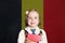Belgium concept with happy child girl in school uniform with book against the Belgian flag background