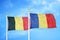 Belgium and Romania two flags on flagpoles and blue cloudy sky