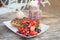 Belgium waffles topped with strawberry, blueberry, ice cream ball and chocolate sauce served with milkshake on wooden table