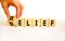 Belief or relief symbol. Businessman turns wooden cubes, changes concept words relief to belief. Beautiful white table white