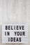 `Believe in your ideas` words on modern board over white wooden background. Flat lay, from above, overhead. Copy space