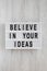 `Believe in your ideas` words on modern board over white wooden surface. Flat lay, from above, overhead