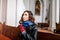 Believing woman sits on a bench in the church and prays to God with hands clasped